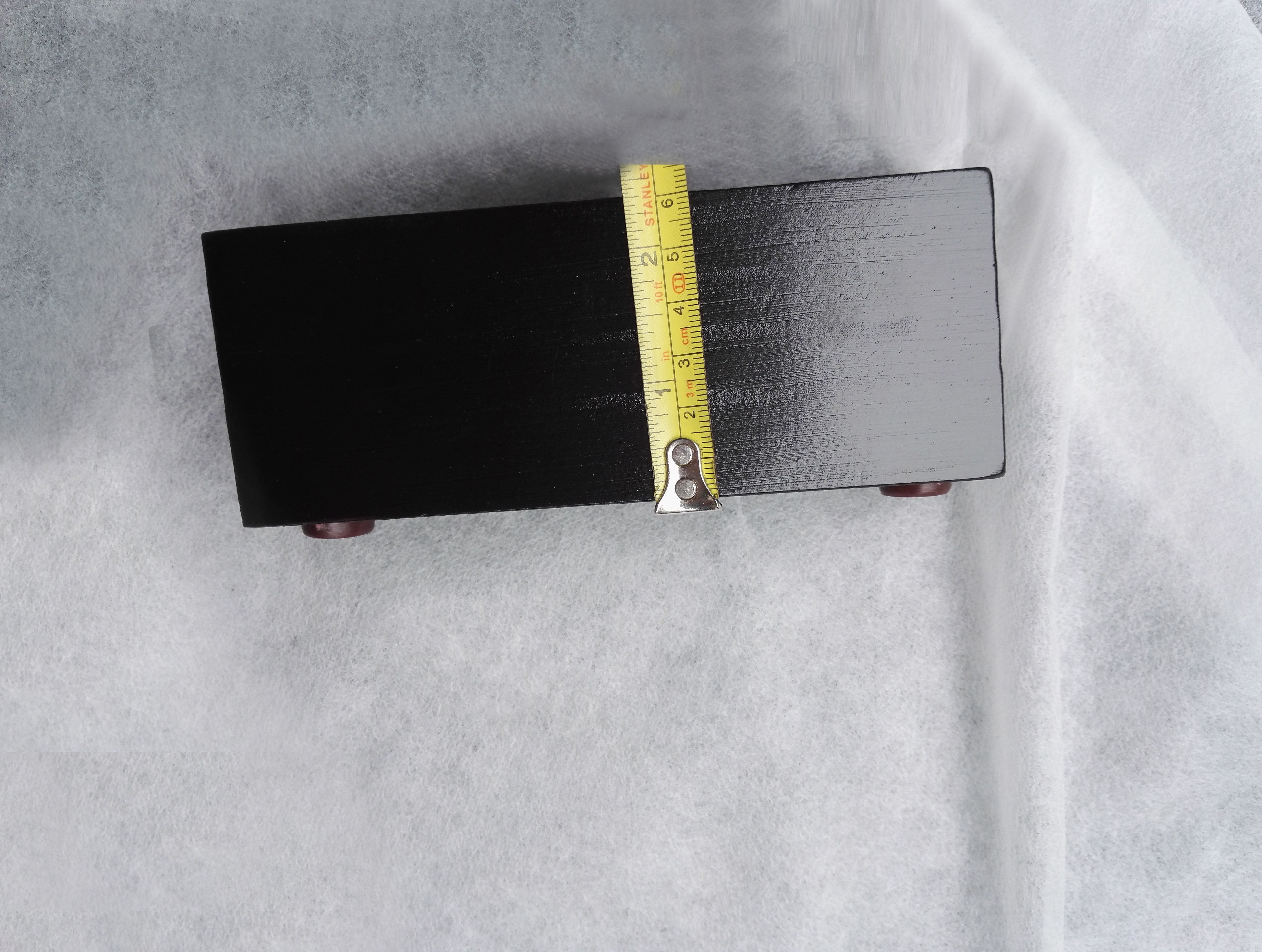 Underside of upholstered headboard showing legs and tape measure