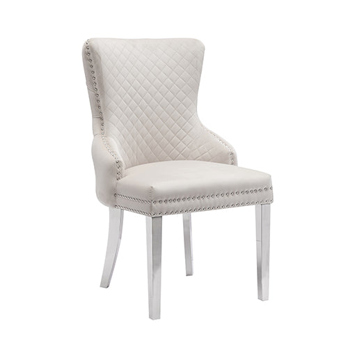 Beige velvet dining chair with diamond tufting, studded trim, and stainless legs