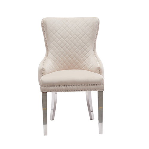 Beige velvet dining chair with diamond tufted back, studded edge, and stainless legs
