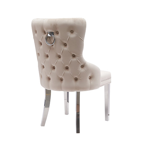 Beige velvet dining chair with button-tufted back, studded trim, and stainless legs