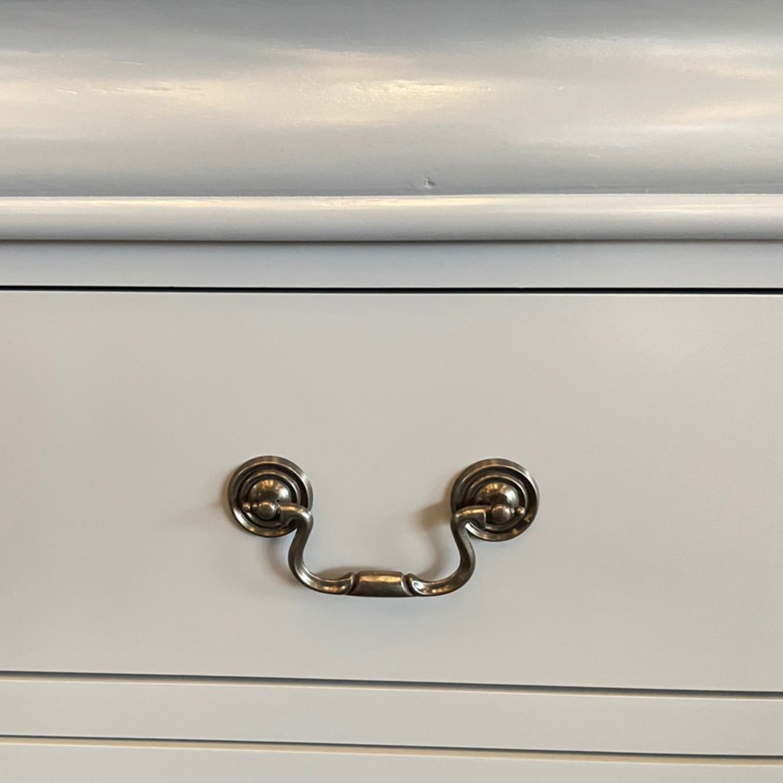 White dresser drawer front with two round metal cup handles