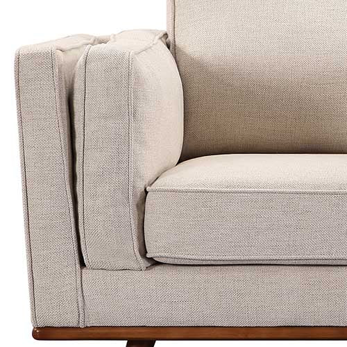 Beige fabric sofa arm with padded armrest and visible wooden base legs