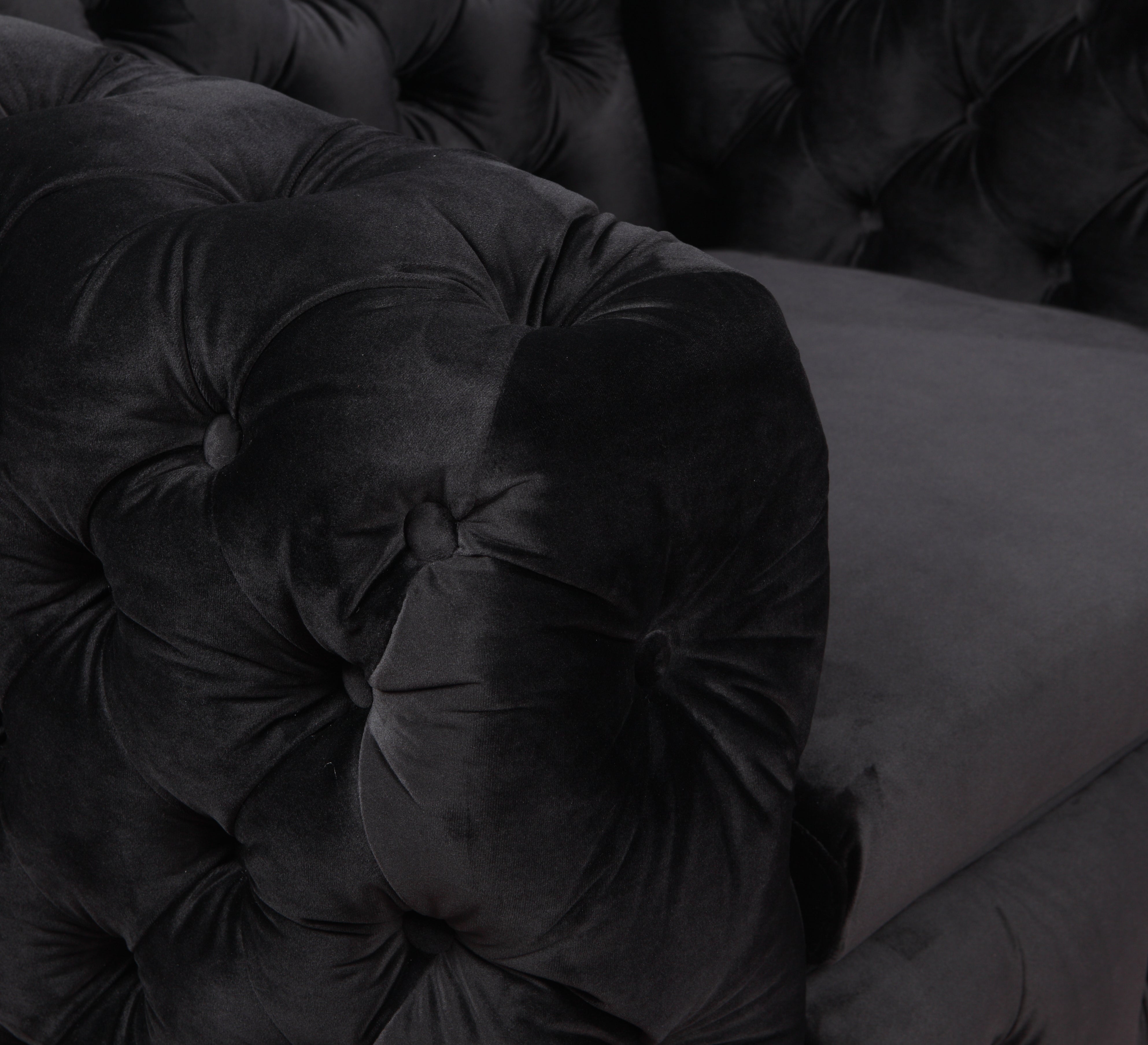 Black velvet armchair close-up of button-tufted cushion and arm