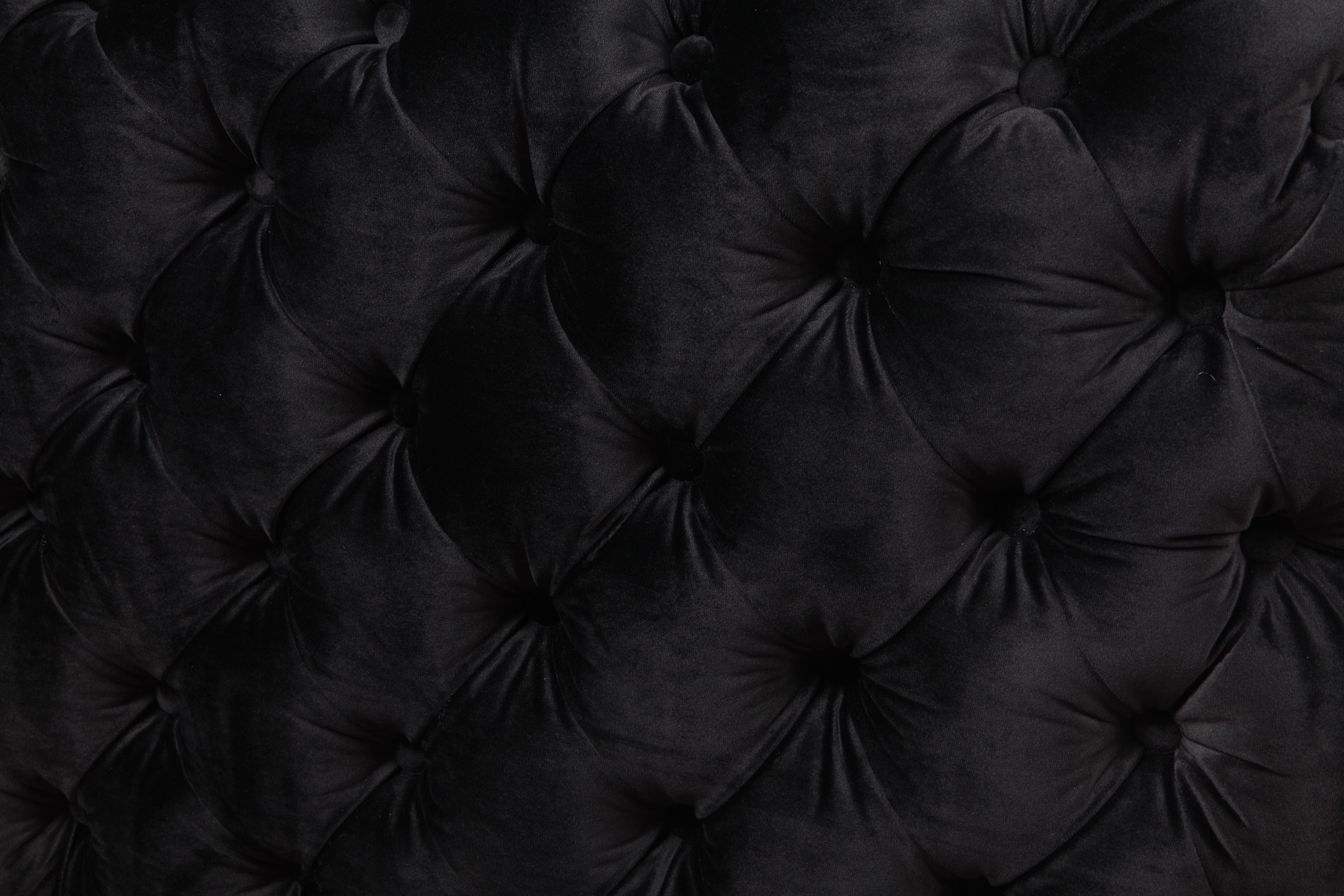 Black velvet armchair back close-up with tufted button pattern