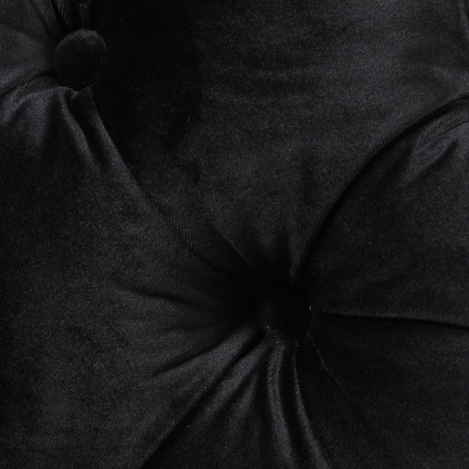 Black velvet armchair seat close-up with tufted buttons and seams