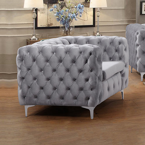 Grey velvet button-tufted armchair in living room setting with wooden floor