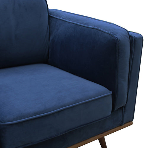 Close-up of dark blue velvet armchair with rolled arms and seat cushions