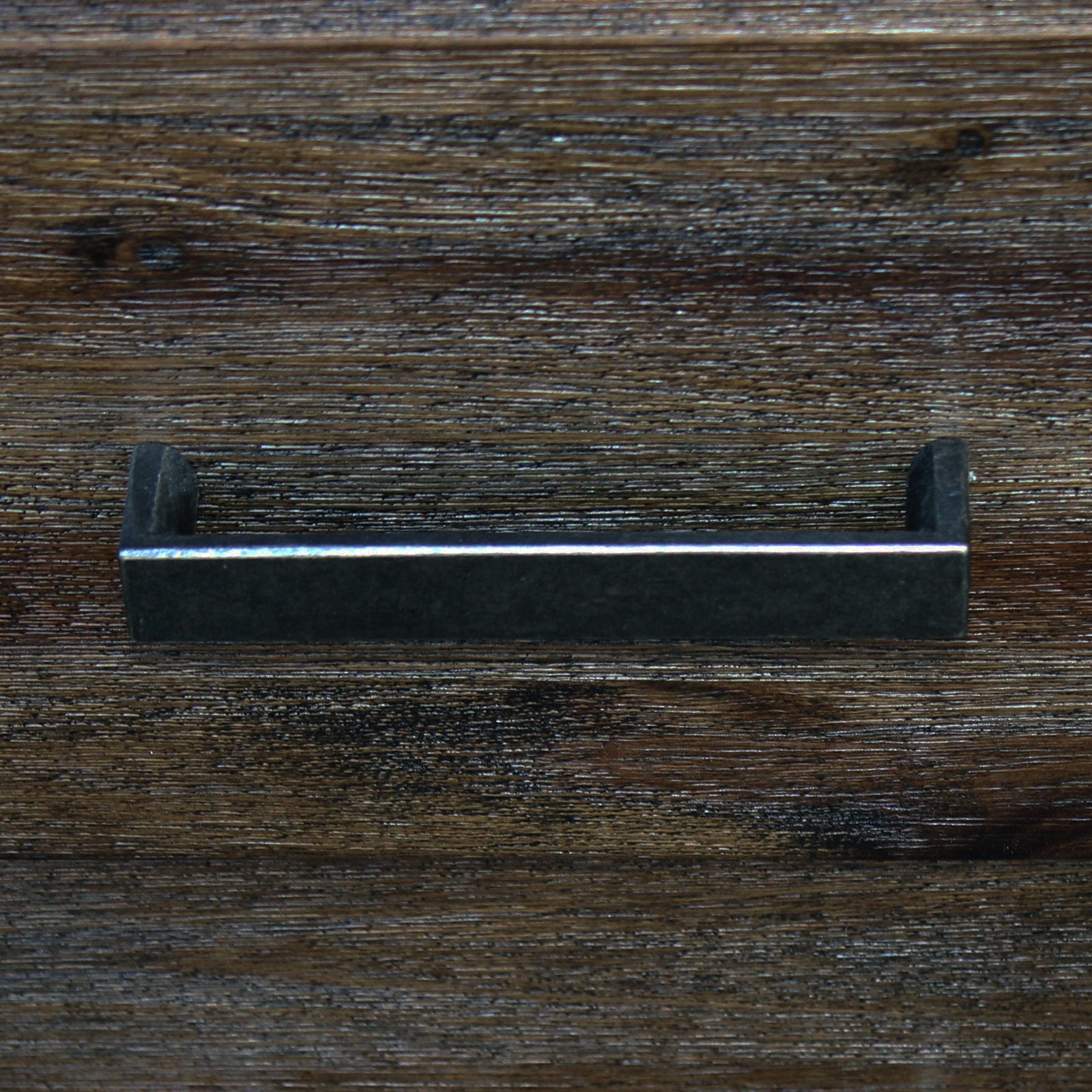 Close-up of a dark wooden drawer front with a metal bar handle