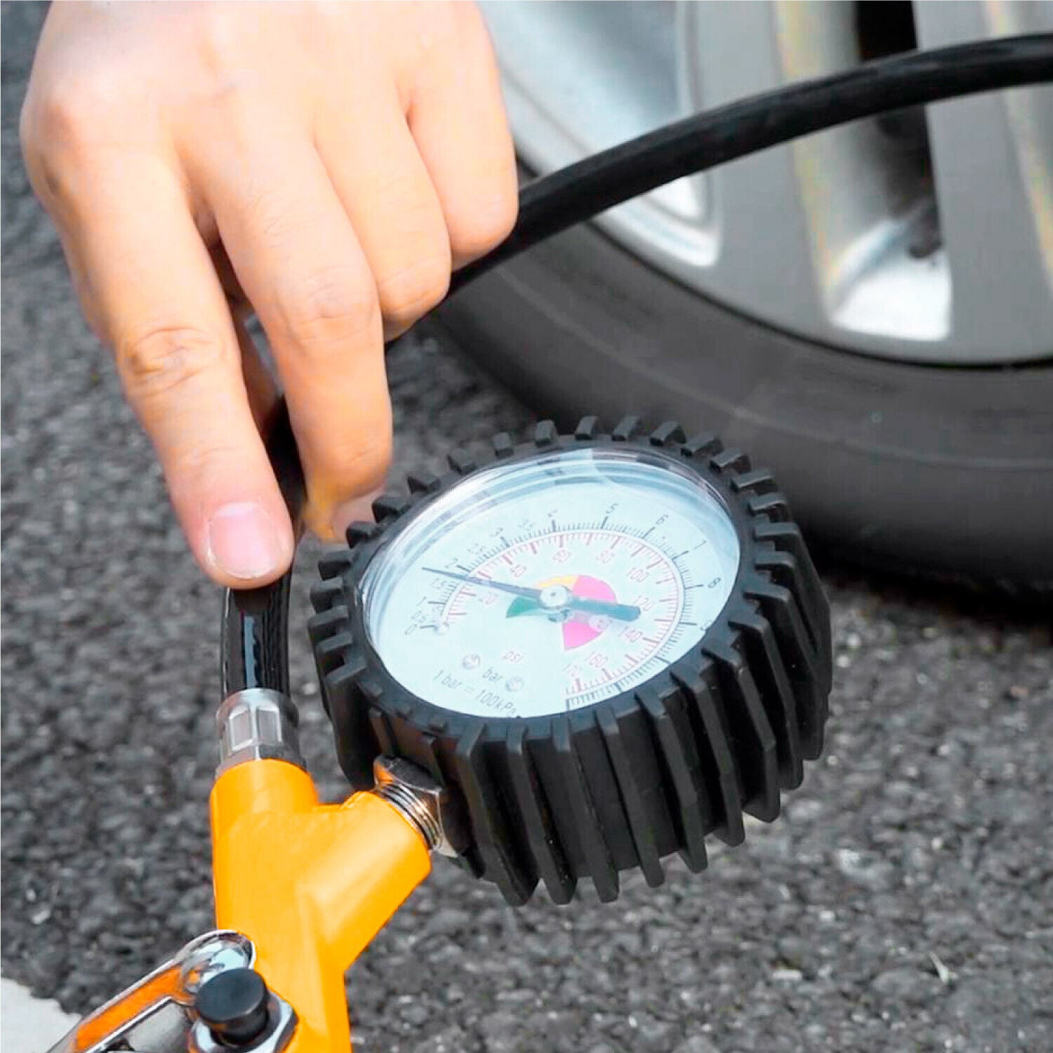 Tyre inflating gauge with air pump nozzle, held on a valve
