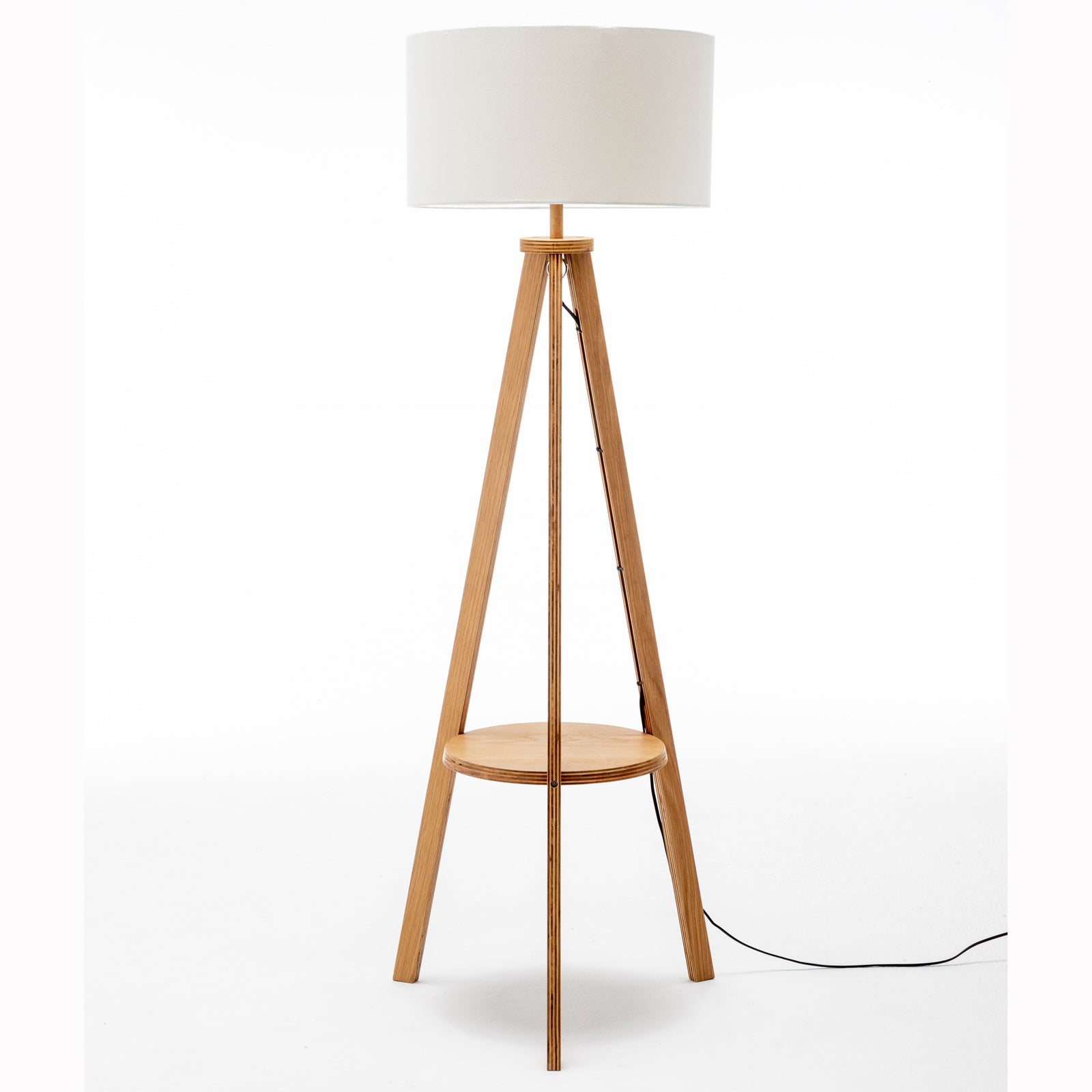 Tripod floor lamp with off-white linen drum shade, round shelf, and cord