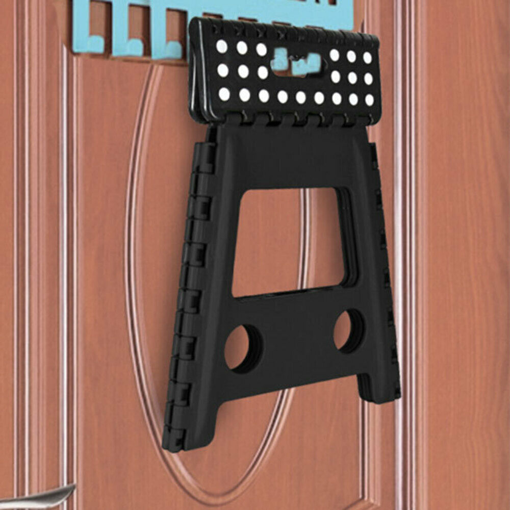 Black plastic folding step stool with perforated platform, angled on a door edge
