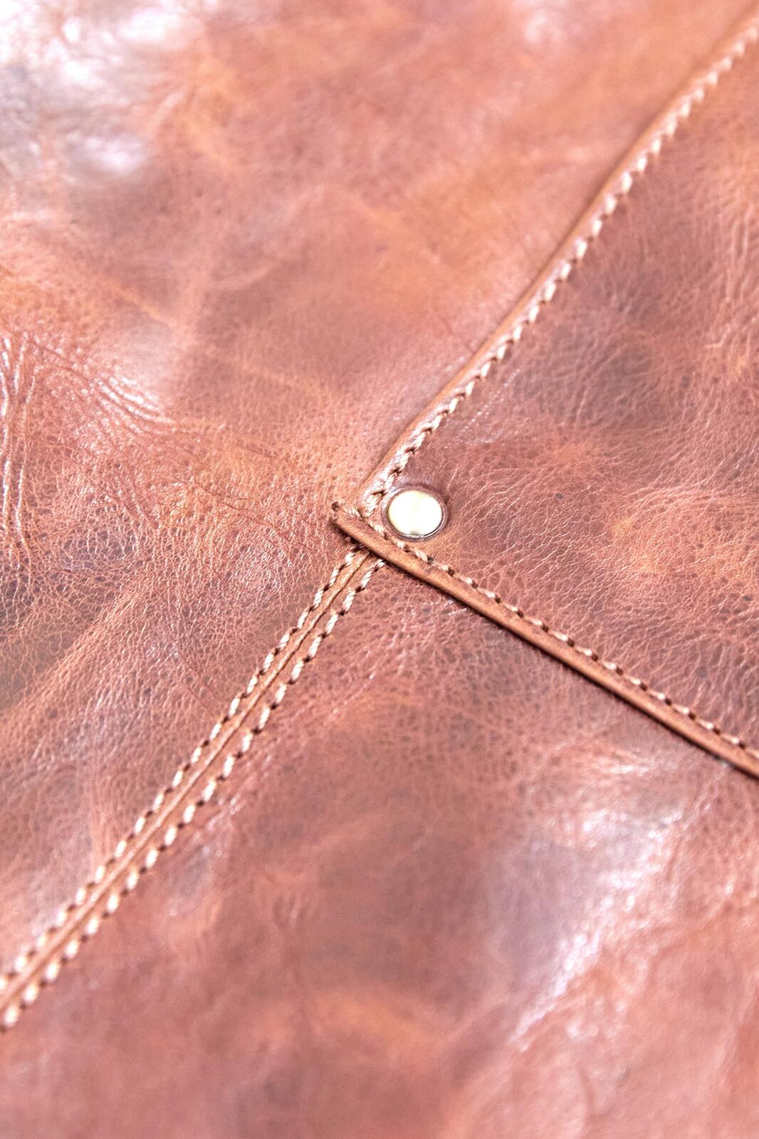 Close-up of cognac leather apron stitching and decorative seam details