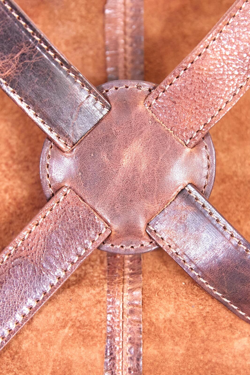 Close-up of cognac leather apron X-cross strap with stitching and rivet