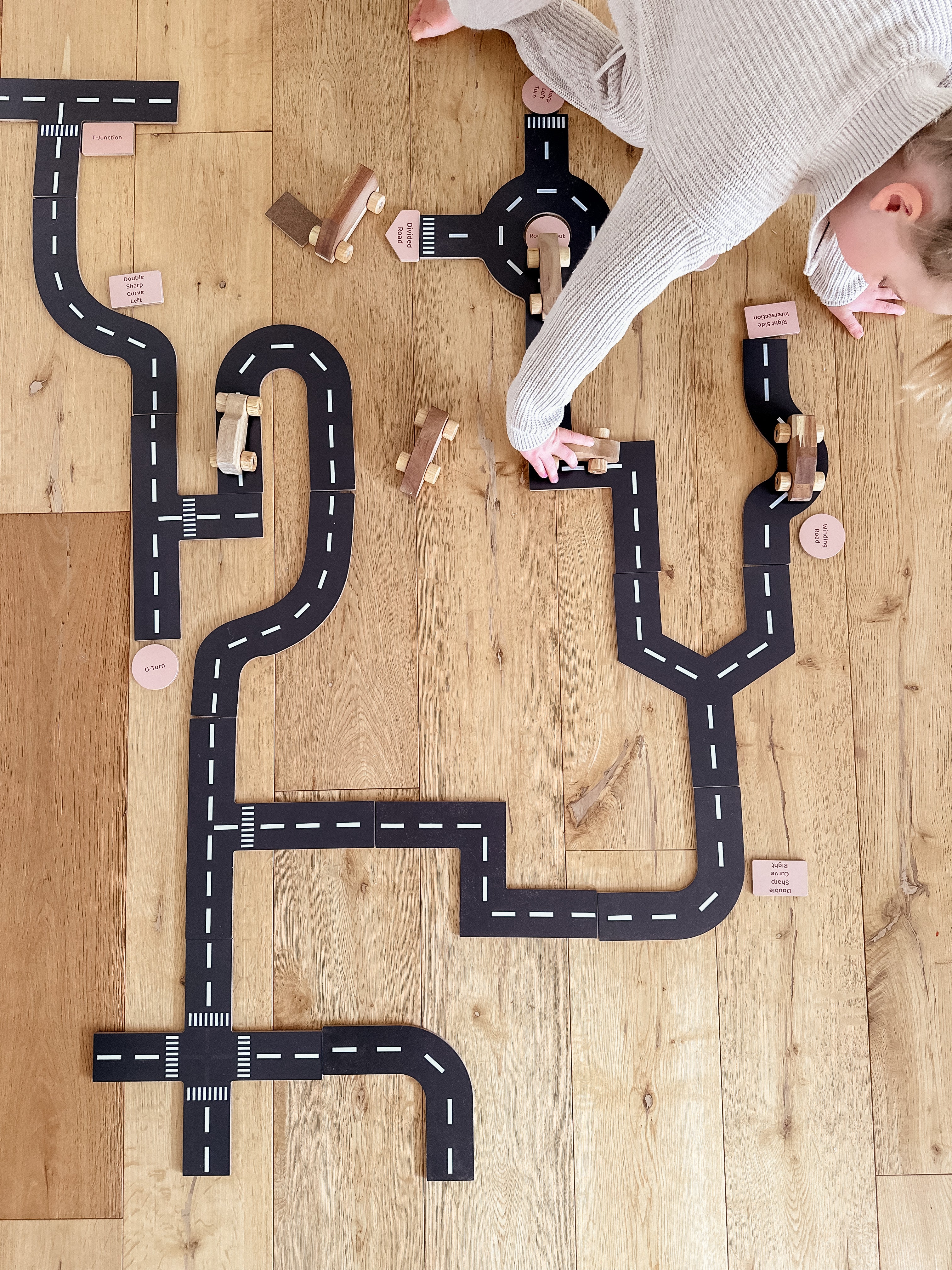 Interlocking toy road play set with black tracks and white lane lines, includes pieces