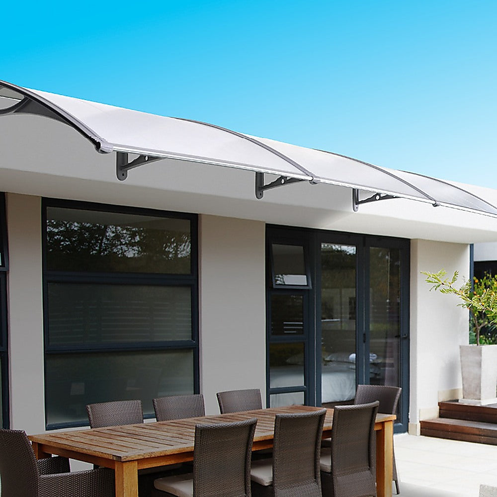 Translucent patio awning cover over door and windows with curved metal supports.