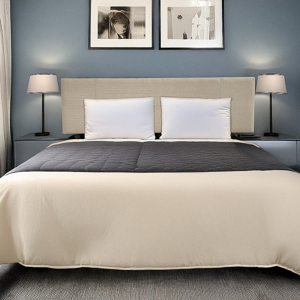 Beige linen king bed headboard behind gray pillows on a light upholstered bed