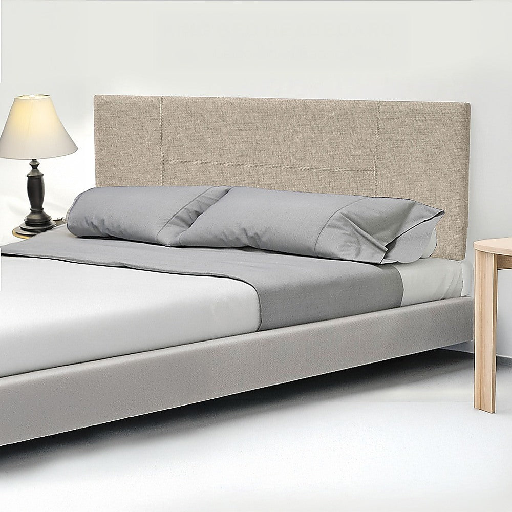 Beige linen king bed headboard behind light gray bedding and pillows