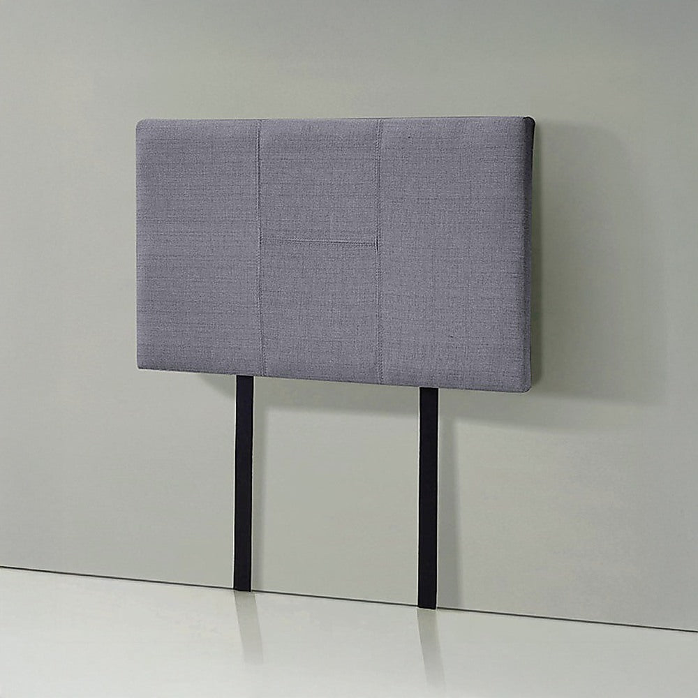 Grey linen headboard with padded panel seams and black legs on floor