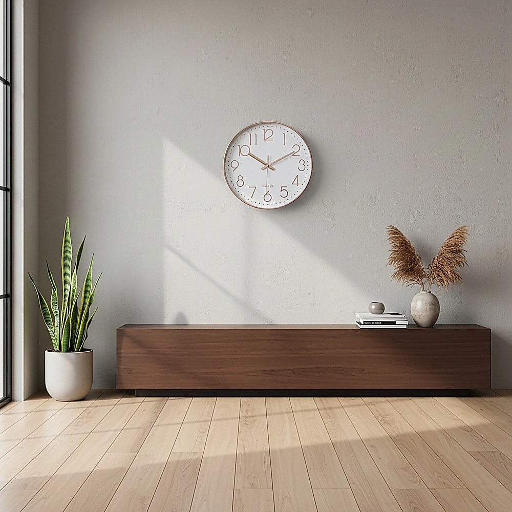 Small rose gold wall clock with white face, roman numerals, and gold hands