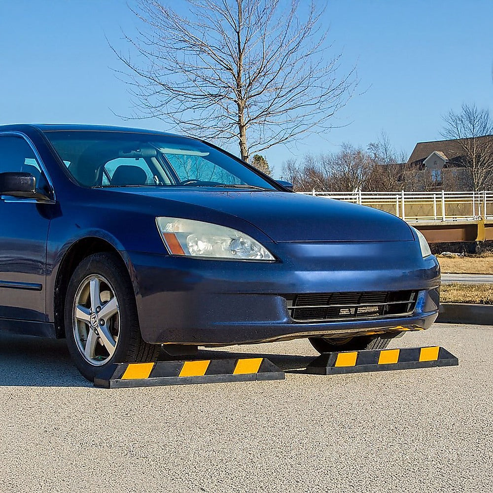 Black rubber wheel stop with yellow reflective pads and a low, angled profile