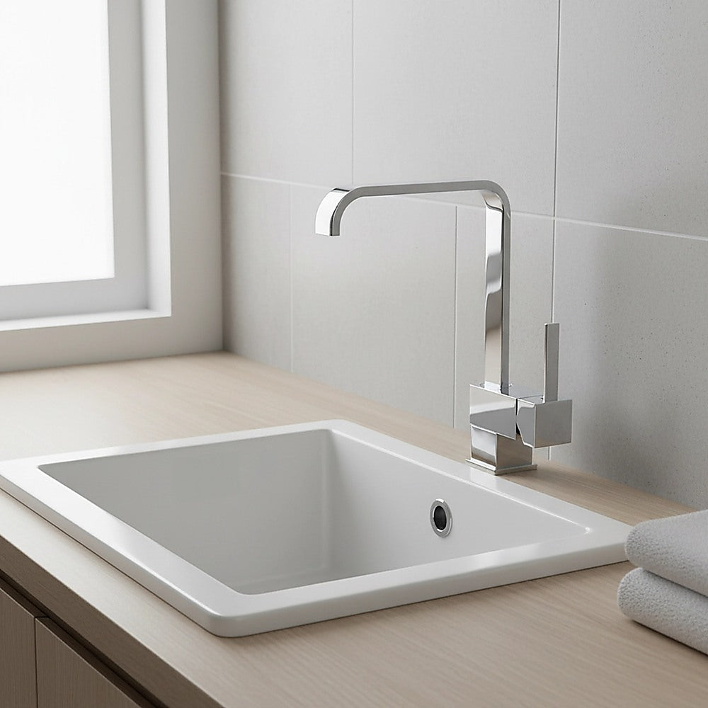 Chrome basin mixer tap mounted on white sink with dual handles