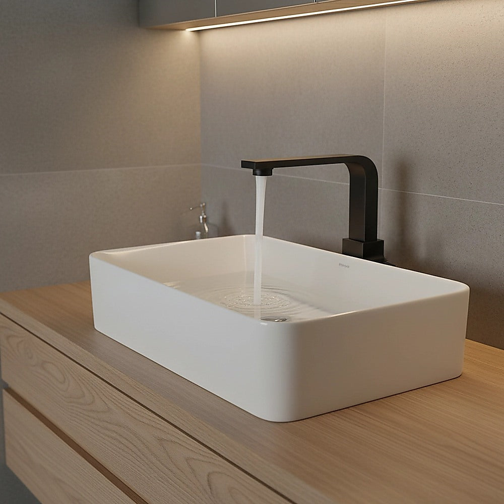 Matte black mixer tap faucet filling a white countertop sink with water