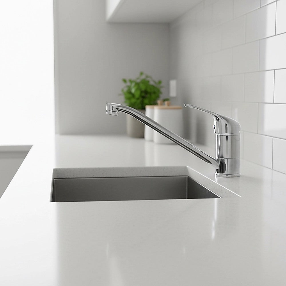 Chrome basin mixer tap with curved spout and single lever over rectangular sink