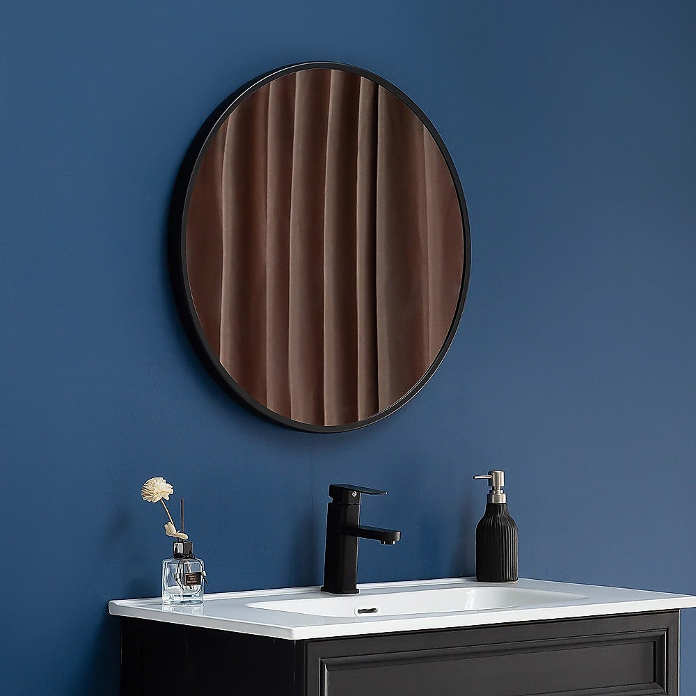 Round wall mirror with dark frame and wood-pattern reflection on the glass.