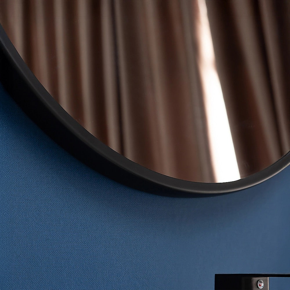 Round wall mirror edge with dark frame and reflective glass surface.