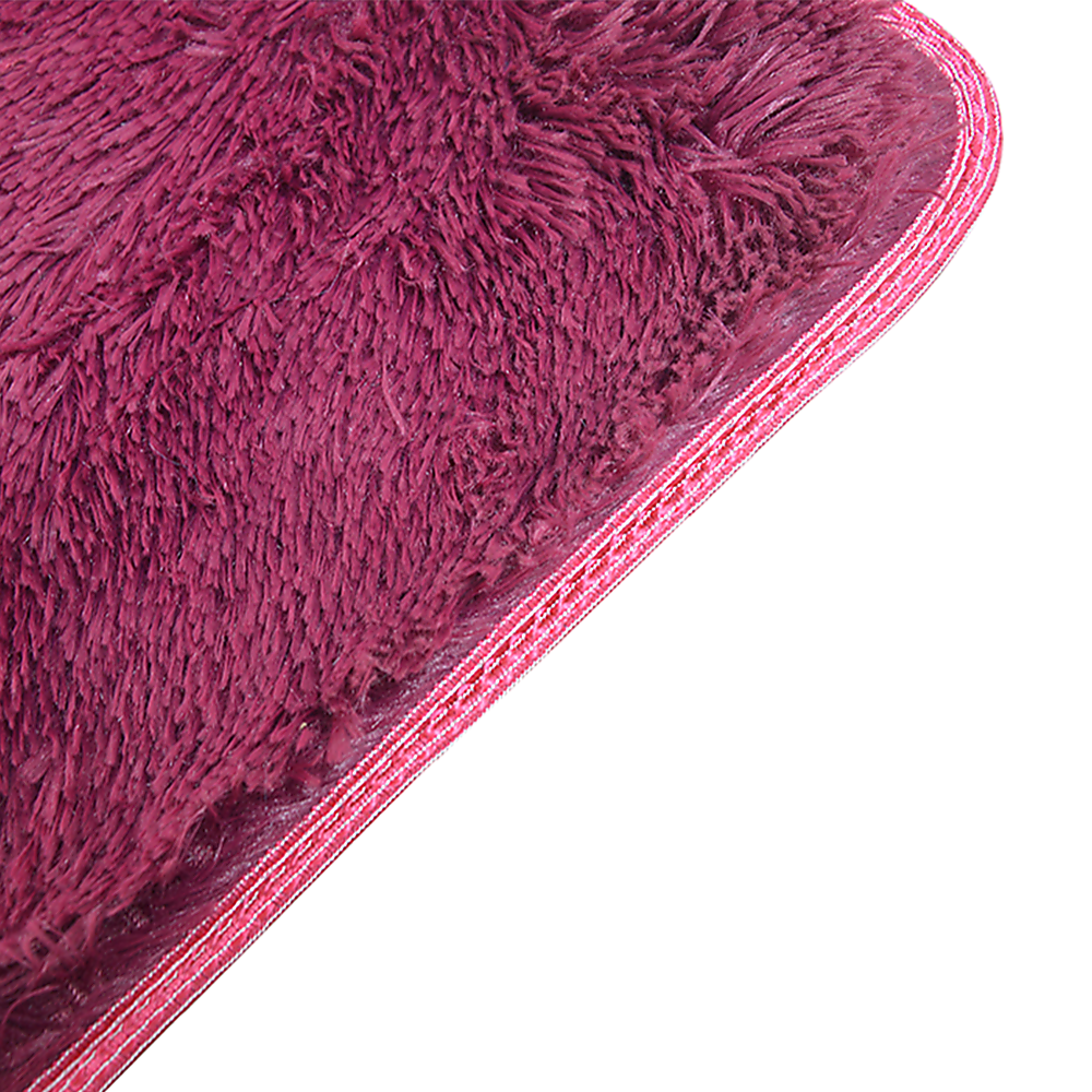 Close-up of burgundy shaggy rug pile and stitched edge trim with pink threads