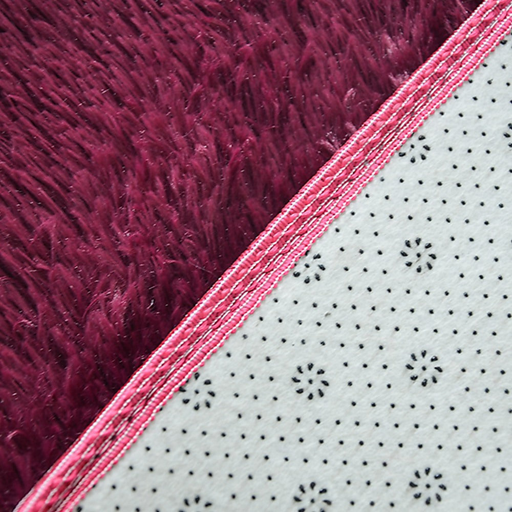 Close-up of rug border: burgundy shaggy side with pink edging and white underside