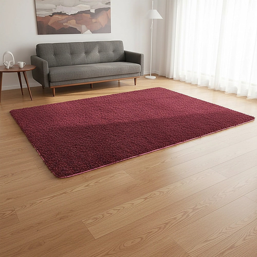 Burgundy shaggy rectangular area rug laid flat, plush pile texture