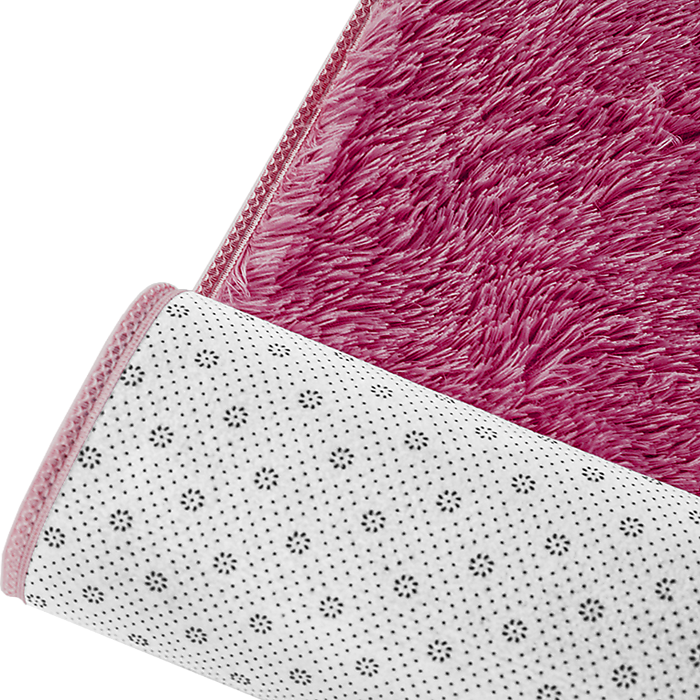Rug corner close-up showing burgundy shaggy top and white underside with dot pattern