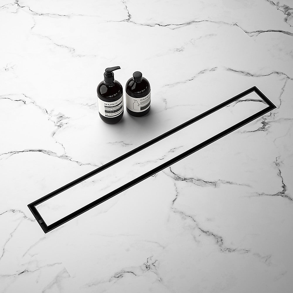 Black linear shower drain grate frame with long slot and center outlet.