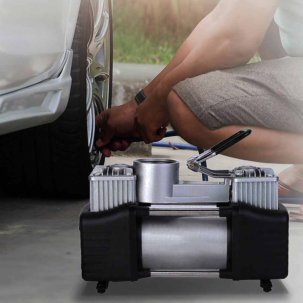 Portable 12V air compressor with pressure gauge and hose, connecting to a vehicle