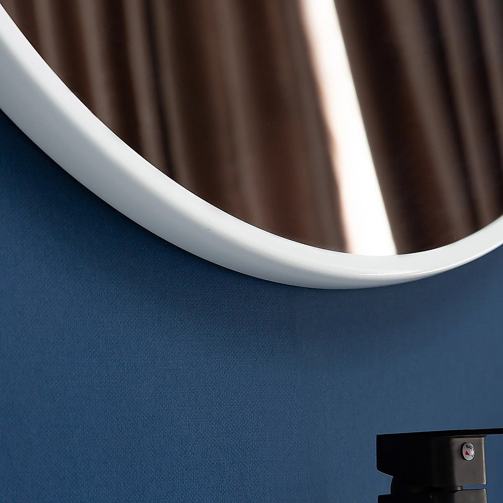 Curved edge of round wall mirror with white rim and reflective glass