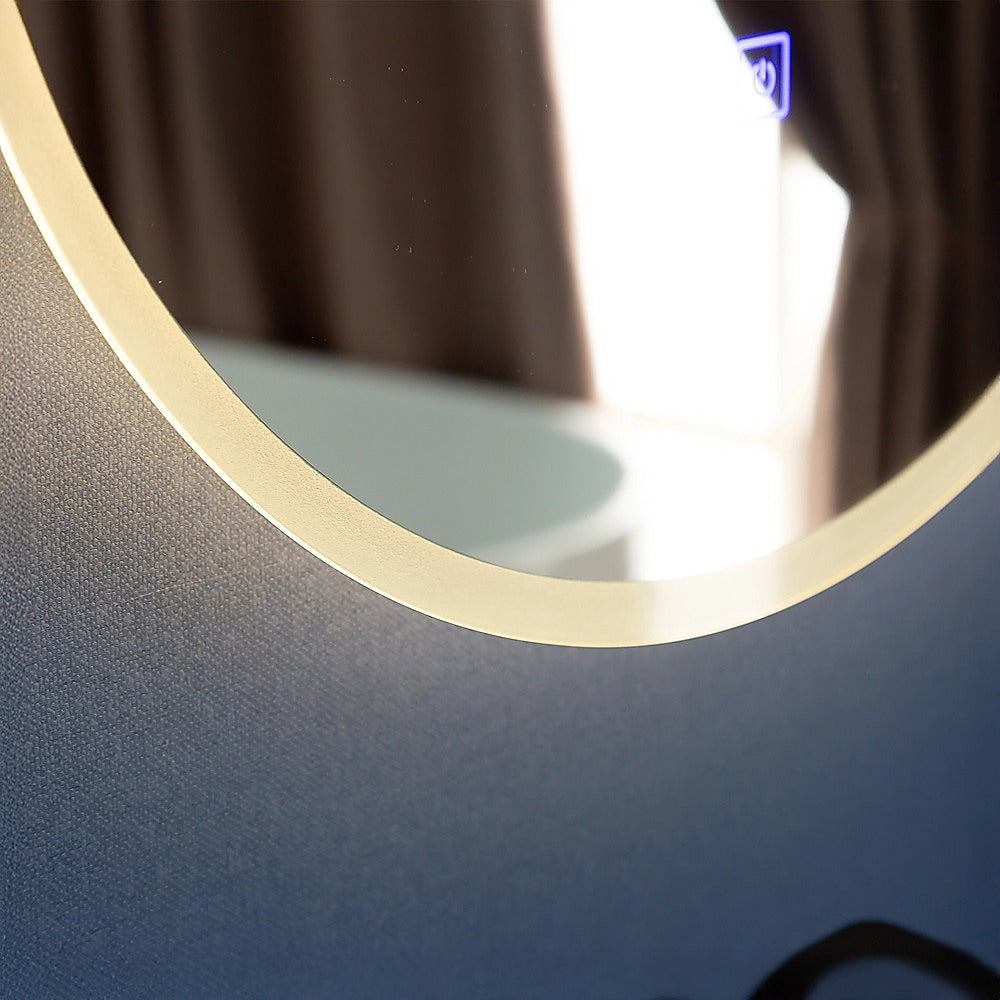 Close view of a round mirror edge showing warm LED glow and reflective surface