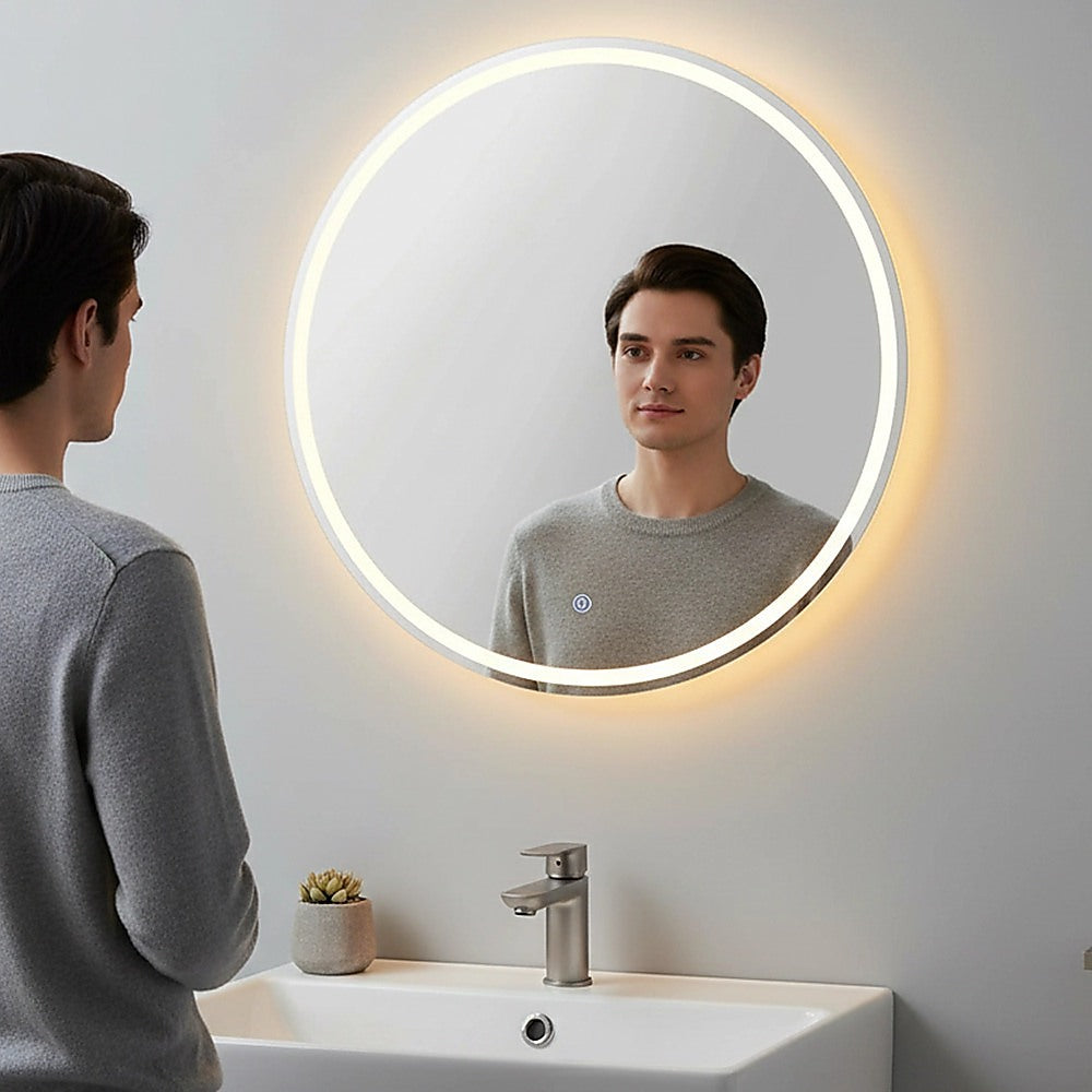 Round LED wall mirror with glowing ring light above a bathroom sink and faucet