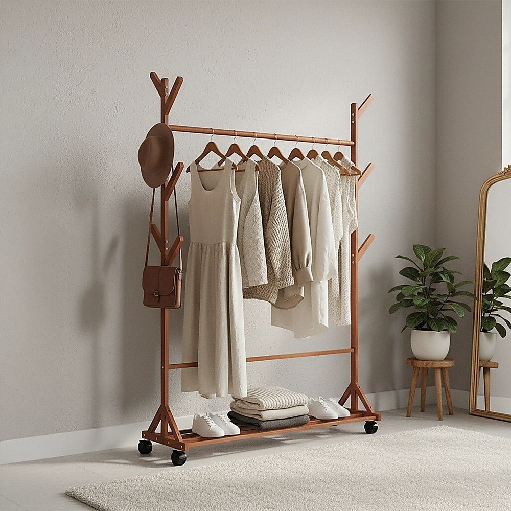Bamboo clothes rack with hanging garments, side bag, and shoe storage shelf