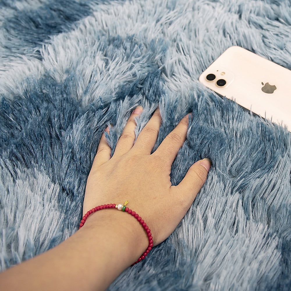 Blue shaggy rug with hand pressing into the soft pile