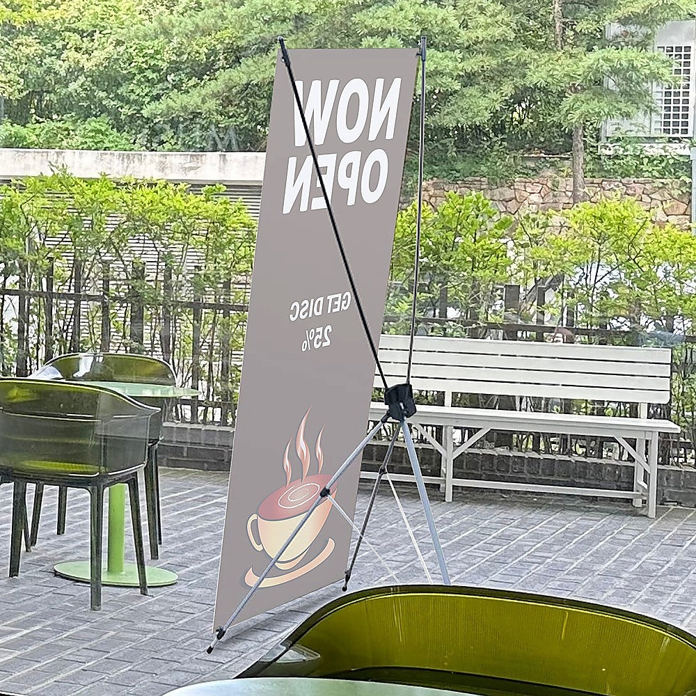 Outdoor X banner stand with gray banner and tripod legs on patio stones
