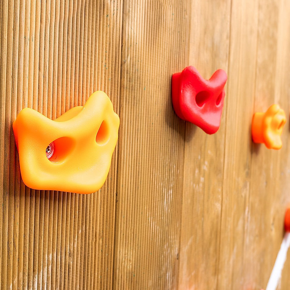 Yellow and red resin climbing holds mounted on a wooden climbing wall.