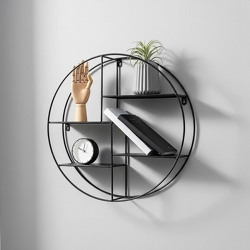 Black circular floating wall shelf displaying decor, including plant and framed items