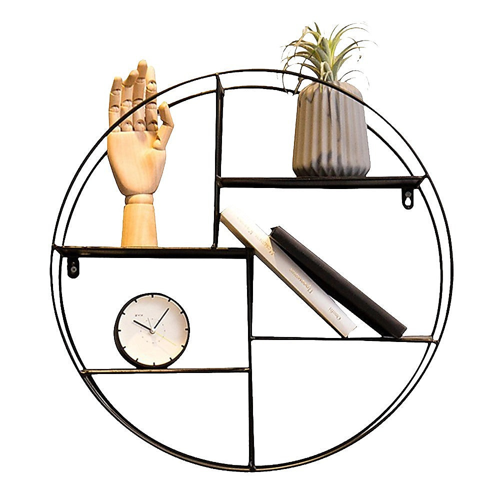 Black circular floating wall shelf with open levels holding decor pieces