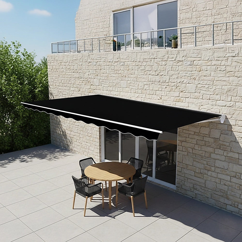 Black retractable awning canopy with scalloped valance installed over patio seating