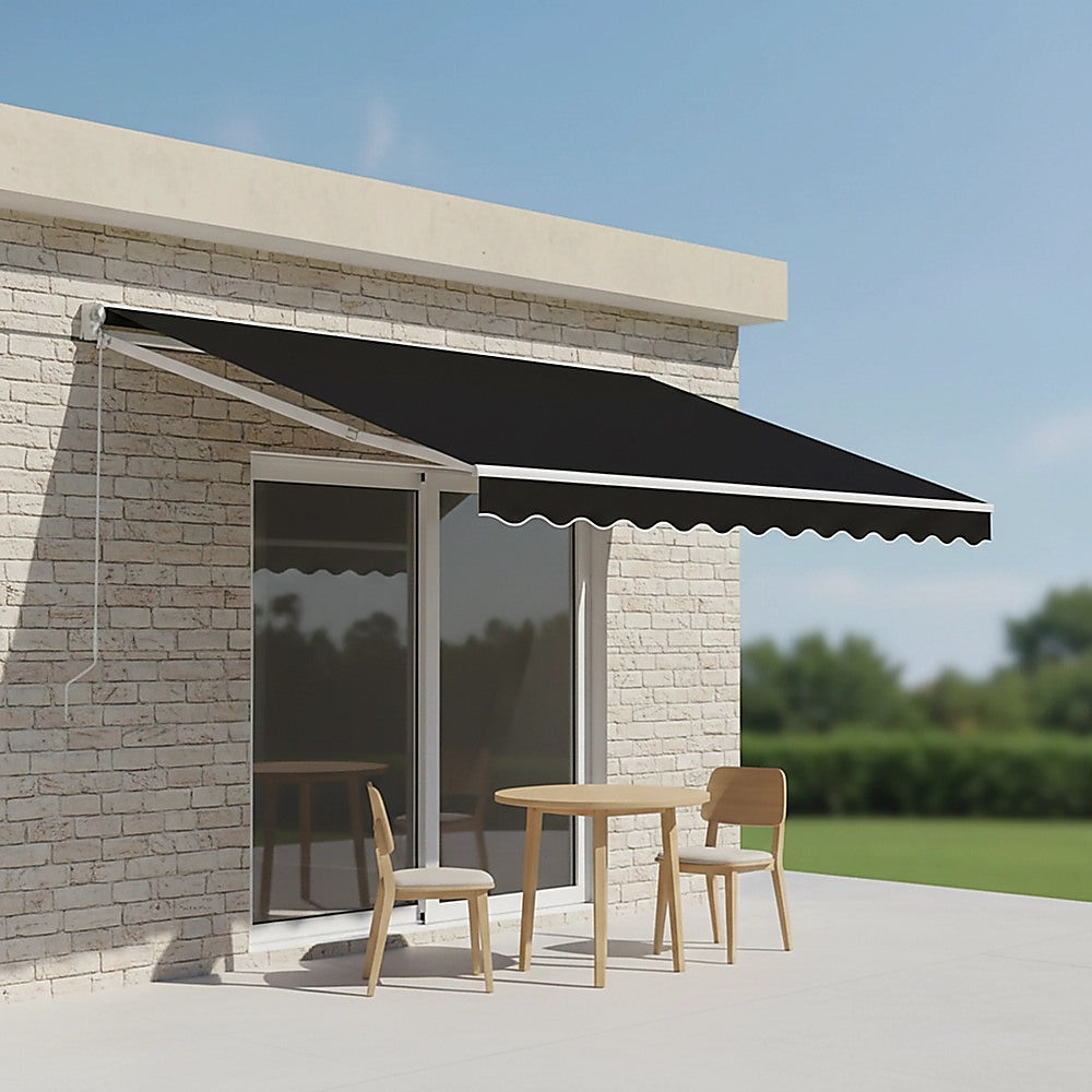 Black retractable arm awning canopy with scalloped valance over patio table and chairs