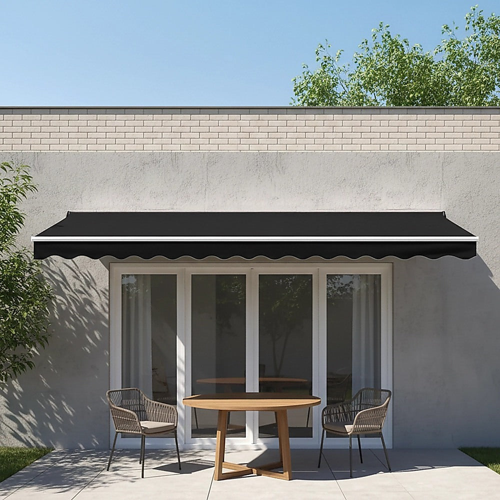 Motorized retractable awning with black canopy over outdoor entry area