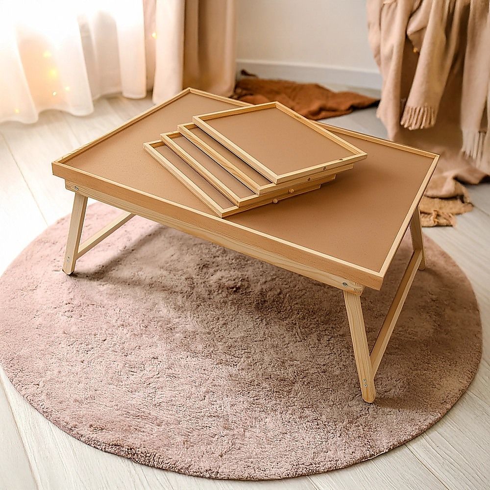 Wooden jigsaw puzzle table with foldable legs and tan board on a rug