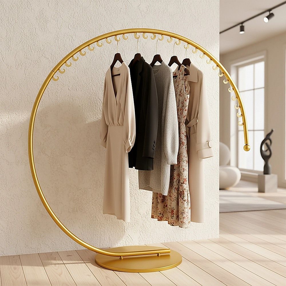 Curved floor clothes hanger rack with gold bar and hanging coats