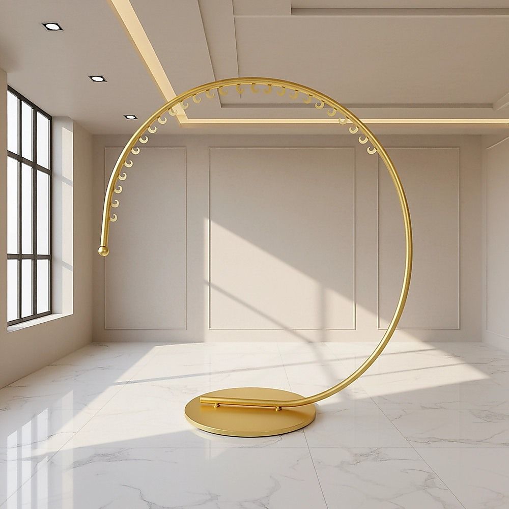 Curved floor-standing clothes hanger rack with gold bar and round base